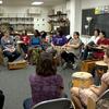 Photo of students in classroom sitting in a circle with percussion instruments in front of them