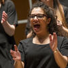 Student with curly hair and glasses singing and clapping hands