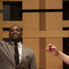 Photo of man in suit gesturing while female student sings during master class