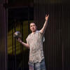 Photo of male opera student in costume and on stage with one hand holding a ball and the other stretched out