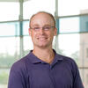 Headshot photo of man in blue shirt and glasses.