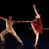 Dancer in a lunge position holding the hand of another dancer one foot and arm raised